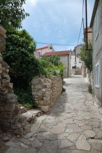 an alley with a stone wall next to a street at Apartman Kristina, studio i soba in Primošten