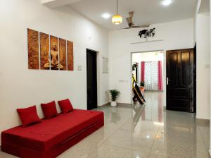 a living room with a red couch and a violin at Happy Buddha Varkala in Varkala