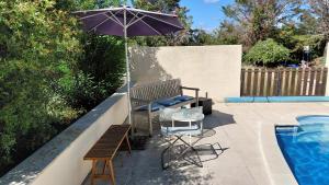 a patio with a bench and an umbrella next to a pool at Gite Mimosa - Private Pool, Sainte-Valière, South of France in Sainte-Vallière