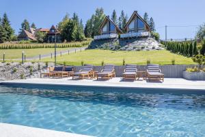 a group of chairs sitting next to a swimming pool at Leśny Wierch luxury spa villas in Bukowina Tatrzańska