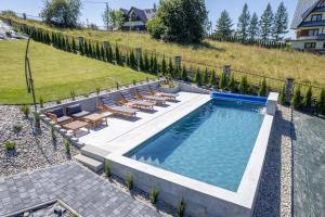 a swimming pool with lounge chairs and a patio at Leśny Wierch luxury spa villas in Bukowina Tatrzańska