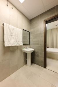 Un baño con lavabo, espejo y bañera. en The Living, en Khor Fakkan