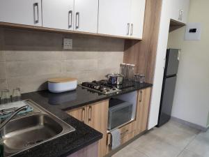 a small kitchen with a sink and a stove at Mhlahlo Guests in Ga-Rankuwa