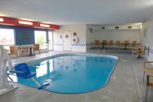 une grande piscine dans une pièce avec chaises et tables dans l'établissement Comfort Inn & Suites Coralville - Iowa City near Iowa River Landing, à Coralville