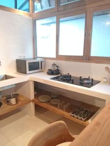 a kitchen with a stove and a microwave at Villa Lumbung Uluwatu 2 in Uluwatu