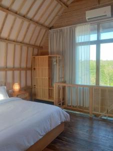 a bedroom with a bed and a large window at Villa Lumbung Uluwatu 2 in Uluwatu