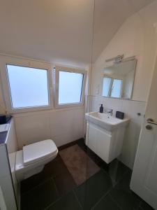 a bathroom with a sink and a toilet and two windows at Bright 3-room apartment - space for family & friends in Tecklenburg