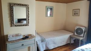 une chambre avec un lit, un miroir et une chaise dans l'établissement Boomerang Cottage B&B - Quintanapalla, à Quintanapalla