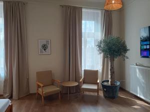 a room with two chairs and a table and a potted tree at Central Apartments in Pápa