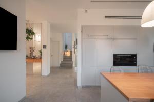 a kitchen with white cabinets and a dining room at Olga Resort - אולגה ריזורט in H̱adera