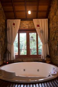 a large bath tub in a room with a window at Pousada Villa Acauã in Visconde De Maua