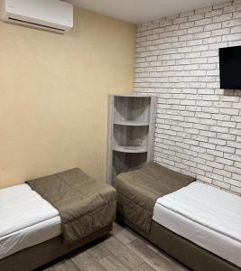 a room with two beds and a tv on a brick wall at Coffee Room in Odesa
