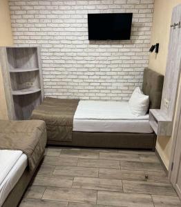 een slaapkamer met 2 bedden en een tv aan een bakstenen muur bij Coffee Room in Odessa +59 foto's