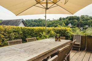 a wooden table with an umbrella on a deck at Villa Louise in Durbuy
