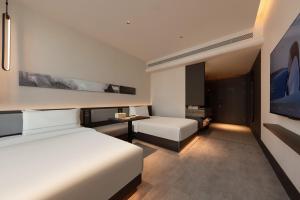 Atour Hotel Hohhot Wanda Plaza, Xinhua Street في هوهوت: غرفة فندقية بسريرين وتلفزيون
