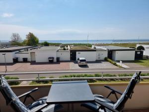 a table and chairs on a balcony with a view of a parking lot at Wohnung Südstrand Glück in Fehmarn