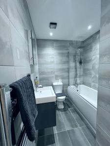 a bathroom with a sink and a toilet and a tub at Luxury Norwich City Centre Apartment - Free Parking in Norwich