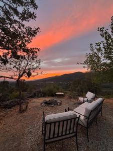 two benches sitting on top of a hill with a sunset at El Encuentro - Casa Rural - in Arenas de San Pedro