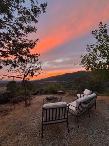 two benches sitting on top of a hill with a sunset at El Encuentro - Casa Rural - in Arenas de San Pedro