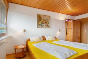 - une chambre avec un lit jaune et un plafond en bois dans l'établissement Ferienwohnung Bodenseeblick, 