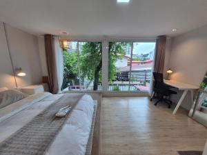a bedroom with a bed and a desk and a large window at Cat House BKK in Bangkok