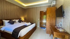 a bedroom with a large bed and a television at Ubud Kerta Prashati in Ubud