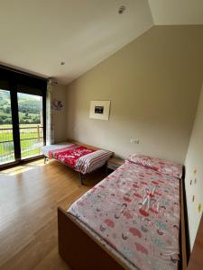 a bedroom with two beds and a large window at Espaciosa con vistas in Villaviciosa