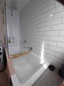 y baño con bañera y azulejos blancos. en Studio Solaris, en Daylesford