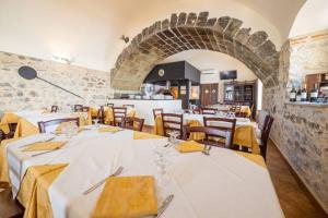 a restaurant with white tables and chairs and a brick wall at Agriturismo Valle dell'Etna in Roccella Valdemone