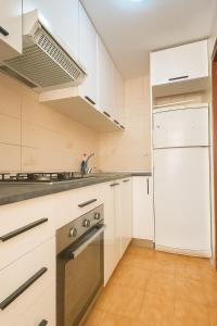 a kitchen with white cabinets and a sink and a refrigerator at Ola Azul Bungalow II in Benidorm