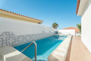 a swimming pool next to a white wall with blue water at Villa Callao Salvaje Sunset in Callao Salvaje