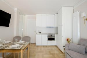 a kitchen and living room with white cabinets and a table at appart terrasse 1 mn de la plage in Nice