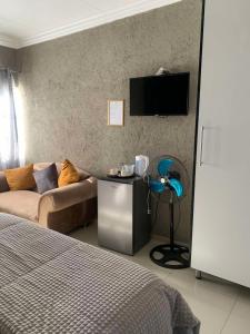 a bedroom with a couch and a tv on the wall at Ivy B&B Guest House in Nelspruit