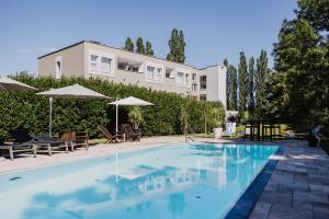 BerghausenEwitsch 13 - Hotel Garni的建筑物旁边有带椅子和遮阳伞的游泳池