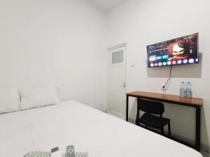une chambre avec un lit et un bureau avec une télévision dans l'établissement Ndalem Tamanan Syariah RedPartner, à Gondowulung 12 autres photos