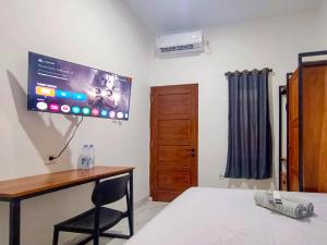 - une chambre avec un bureau et une télévision murale dans l'établissement Ndalem Tamanan Syariah RedPartner, à Gondowulung