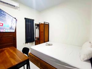 une chambre avec un lit, un bureau et une télévision dans l'établissement Ndalem Tamanan Syariah RedPartner, à Gondowulung