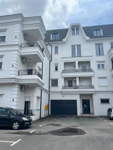 a large white building with a car parked in a parking lot at White Palace in Palić +7 photos