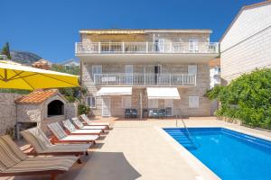 a house with a swimming pool and chairs and a building at Apartments Bezmalinović 2 in Bol