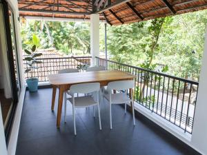 a wooden table and chairs on a balcony at Eema Homestay Marari in Mararikulam