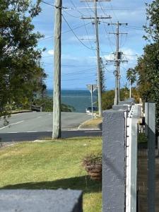 a fence with a view of a street and the ocean at Cozy guest suite in Margate, 200 mts from beach in Woody Point