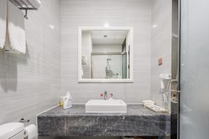 a white bathroom with a sink and a mirror at SEEU Designer Apartment in Shenzhen