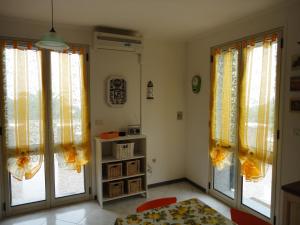 トッレ・ヴァードにあるGiglio di Mareの黄色いカーテン付きの大きな窓2つが備わる客室です。
