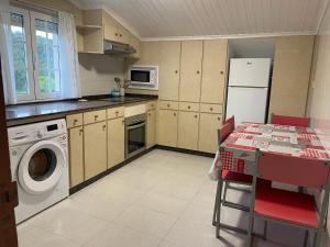a kitchen with a washing machine and a table with chairs at Lar Etxea O Barqueiro in O Barqueiro