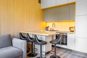 a kitchen with a bar with stools and a couch at SKY Home- Piwna Wood -Manufaktura, Parking, Dostęp na Kod in Łódź
