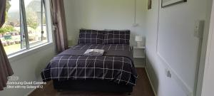 a bed in a small room with a window at Oak Lodge in Taheke
