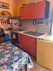 a kitchen with red cabinets and a sink and a table at La Casa Arancione in Lacedonia