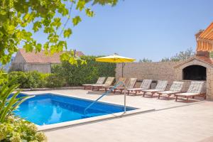 a swimming pool with lounge chairs and an umbrella at Apartmani Bezmalinović in Bol