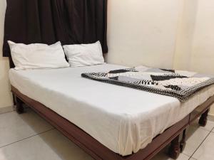 a bed with white sheets and pillows on it at HOTEL OM VADODARa in Vadodara