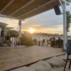 un grupo de personas sentadas en una terraza viendo la puesta de sol en Un pequeño lujo a pocos metros de la playa, en Piles